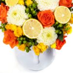 Floral Arrangement with Yellow-Orange Roses in White Glass Case